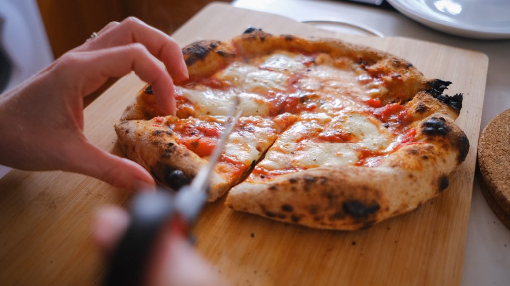 Person grabbing a slice of cheese pizza