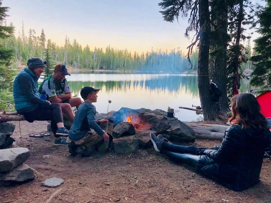 Camping and roasting marshmallows by a lake.