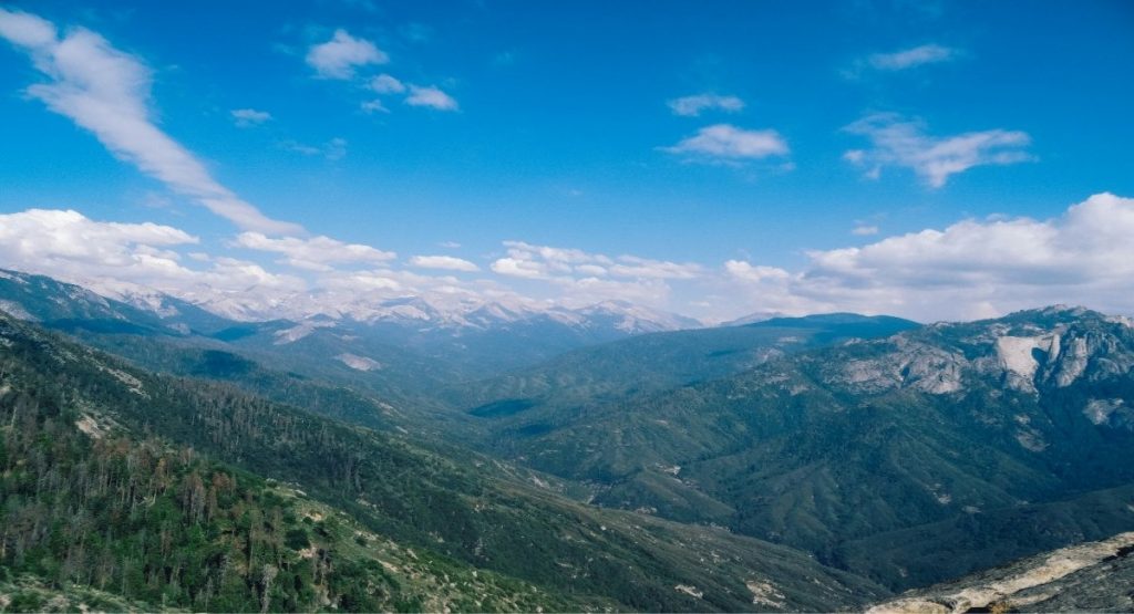 Panoramic view of a forested mountain valley with granite peaks and snow-dusted ridgelines at Sequoia National Park