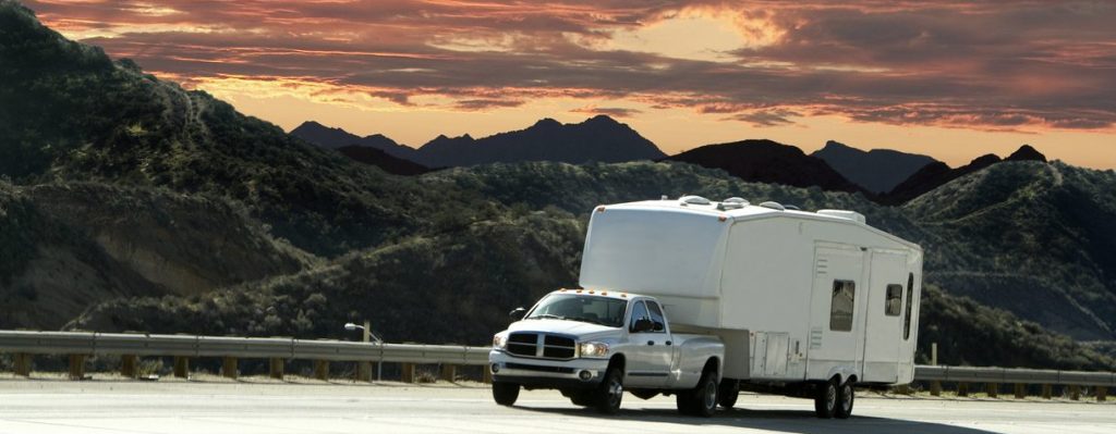 Towing a trailer. A truck pulling a trailer with a beautiful sunset in the background.