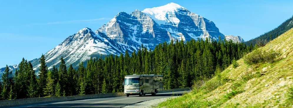 RVing in Canada. Luxury Class A motorhome drives on mountain road near Banff, Alberta, Canada